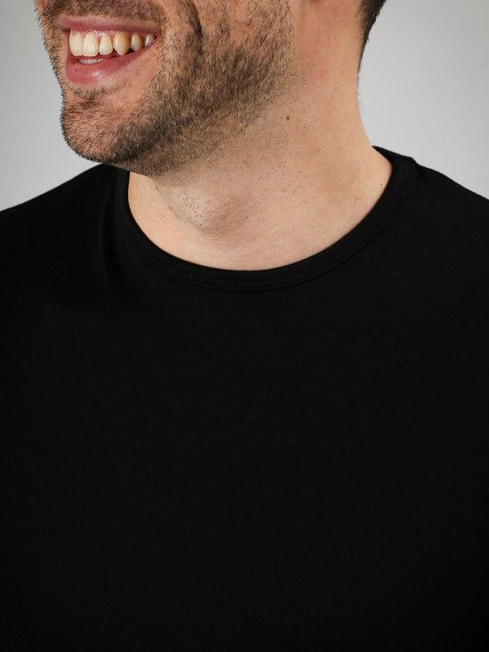 Close-up van een man met een zwart Suitable T-shirt, de ronde hals is zichtbaar.