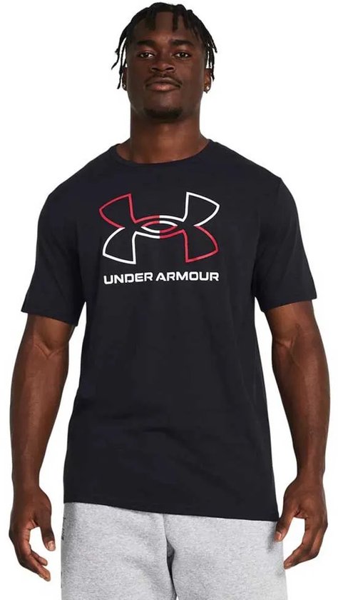 Man met dreadlocks draagt een zwart sportshirt met een grote rood-witte UA-logo opdruk. Grijze sportbroek.