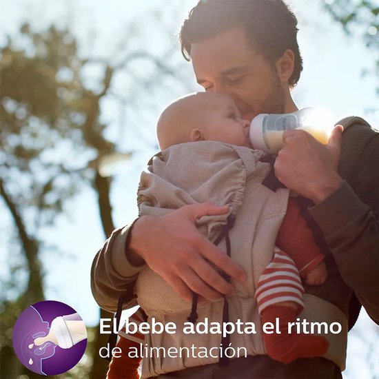 Een vader draagt een baby in een draagzak en geeft de baby een Philips Avent babyfles. Tekst: 'El bebe adapta el ritmo de alimentación'.
