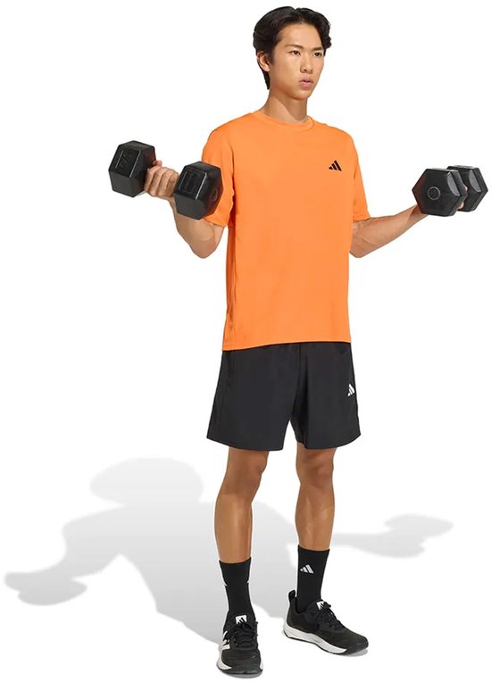 Oranje Adidas sport T-shirt met korte mouwen en zwart Adidas logo, gedragen door een man die traint.