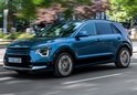 Blauwe Kia Niro SUV met zwarte accenten en zilverkleurige velgen, rijdend op een straat.
