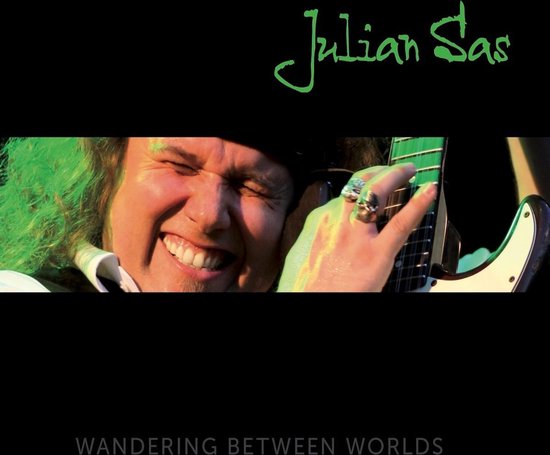 Close-up van Julian Sas die glimlacht, met zijn handen op een gitaar. De tekst 'Julian Sas' en 'WANDERING BETWEEN WORLDS' staan op de hoes.