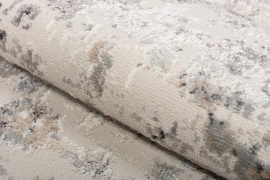 Détail de la texture douce d'un tapis gris clair au motif subtilement délavé.
