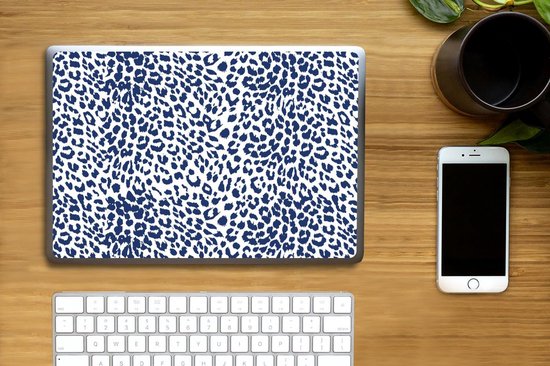 Ordinateur portable avec imprimé léopard bleu, clavier et smartphone sur un bureau en bois.
