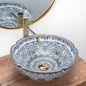 Wastafel met bloemvormige rand en blauw-witte bloemenmotieven, met gouden kraan.