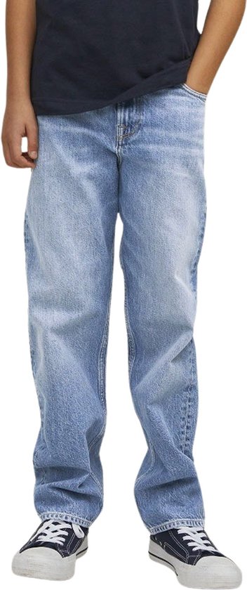 Jongen in een lichtblauwe, wijde spijkerbroek met een donker T-shirt en blauw-witte sneakers.