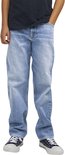 Jongen in een lichtblauwe, wijde spijkerbroek met een donker T-shirt en blauw-witte sneakers.
