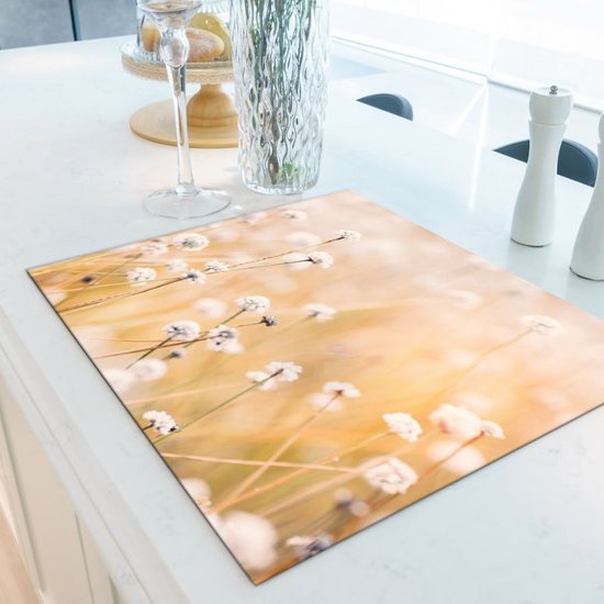 Snijplank met een zachte focus op kleine witte bloempjes in warm, gouden licht.