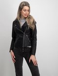 Model in zwarte bikerjack met ritsen, gestreepte top en grijze jeans.