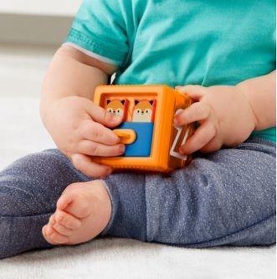 Babyhandjes spelen met een oranje Fisher-Price blok met twee vosjes erin.