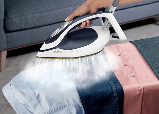 Een vrouw gebruikt de Tefal Pro Express Ultimate II stoomstrijkijzer om stoom te genereren op een blauwe, denim en roze blouse.