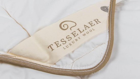 Close-up van het label van een wit dekbed met beige rand, met de tekst TESSELAER LUXURY WOOL.