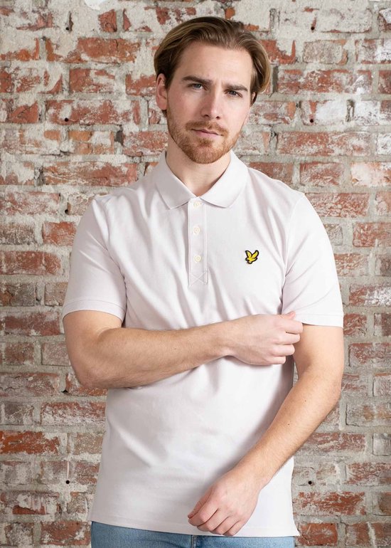 Man in lichtpaars Lyle & Scott poloshirt met korte mouwen, opgestoken kraag en gele vogel-logo op de borst.