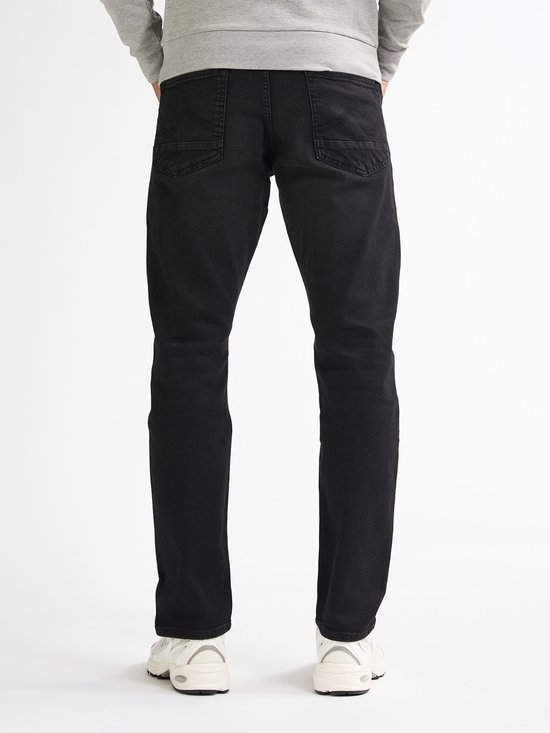 Man van achteren gezien, draagt een grijze sweater en zwarte jeans.