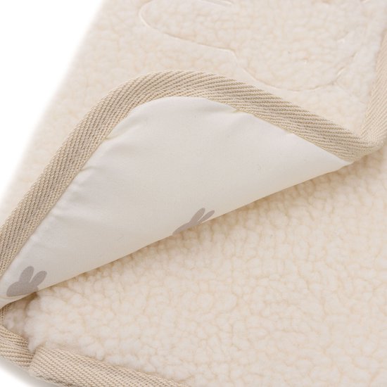 Close-up van een crèmekleurige teddy verschoonmat met beige rand. De binnenkant toont een Nijntje print.
