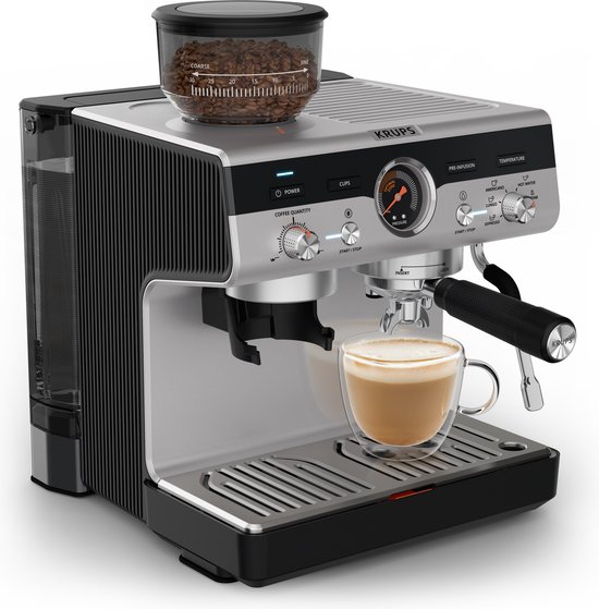 Zilverkleurige Krups espressomachine met ingebouwde grinder en een espresso met schuim in een glas.