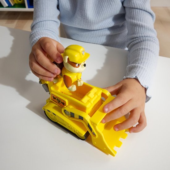 Kind speelt met gele Paw Patrol bulldozer speelgoed met Rubble figuur.