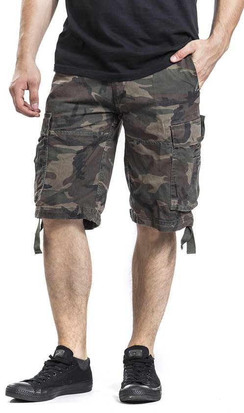 Man met camouflage cargo shorts, met meerdere zakken en zwarte sneakers.