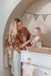 Moeder met baby in rotan aankleedmand, moeder houdt doekje met hartjes vast.