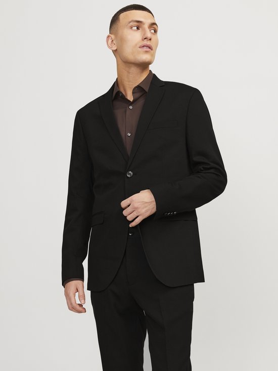 Man in zwart JACK & JONES blazer met bruine blouse. De blazer heeft een reverskraag en sluit met knopen.
