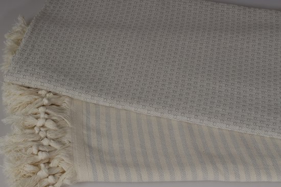 Lichtgrijze hamamdoek met textuur en beige franjes, opgevouwen.