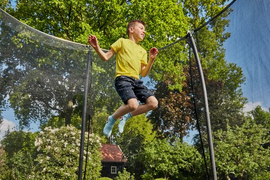 Jongen in geel shirt springt hoog op een rechthoekige Salta trampoline met veiligheidsnet.