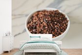 Behang - Fotobehang Gemalen cacaobonen in een keramische kop op een marmeren tafel - Breedte 330 cm x hoogte 220 cm