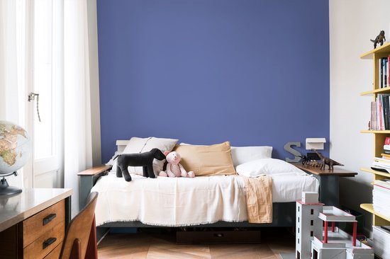 Kinderkamer met een bed, speelgoed en een blauwe muur.