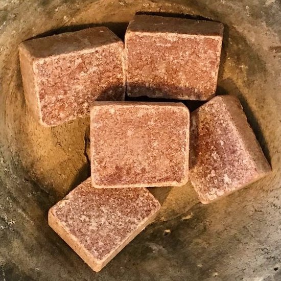 Vijf bruine, korrelige amberblokjes in een stenen mortier.
