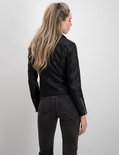Model in zwarte bikerjack, gestreepte top en grijze jeans, van achteren gezien.