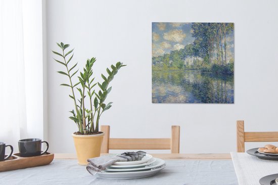 Tableau de Claude Monet: Peuples au bord de l'Epte, suspendu au-dessus d'une table à manger avec une plante et des chaises.