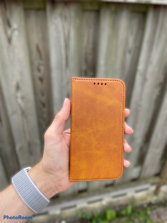 Main avec un étui de téléphone brun en cuir pour un iPhone 12 Pro Max.