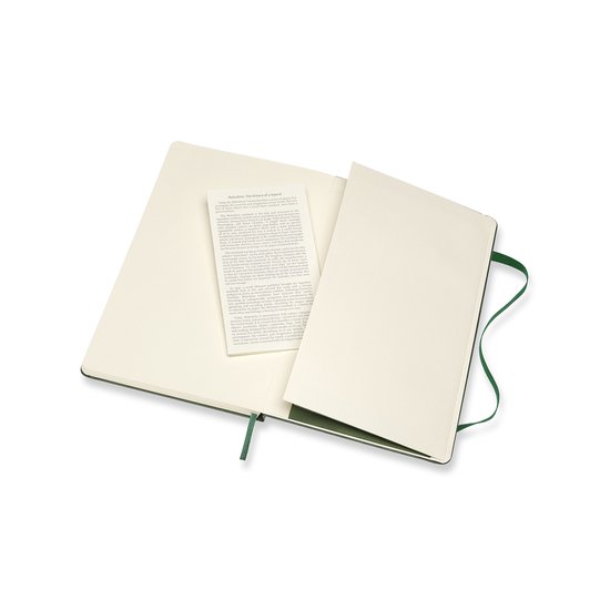 Open Moleskine notitieboek met crème-kleurige, gestippelde bladzijden en een boekje met tekst, in mirtegroen.