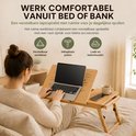 Vrouw werkt comfortabel vanuit bed op een houten laptoptafel. Met verstelbaar werkblad, inklapbare poten, lade en bekerhouder.