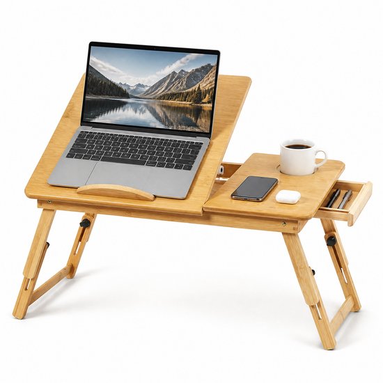 Houten laptoptafel met een laptop, smartphone, oordopjes, mok koffie en pennen in de lade.