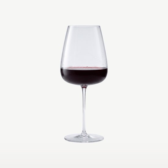 Un verre à vin rempli de vin rouge sur fond blanc.