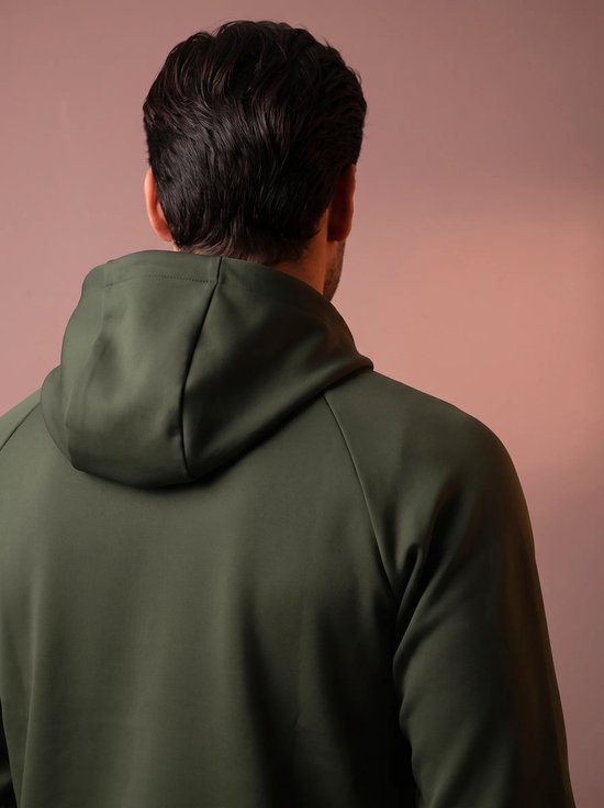 Man van achteren gezien, draagt een olijfgroene hoodie met capuchon.