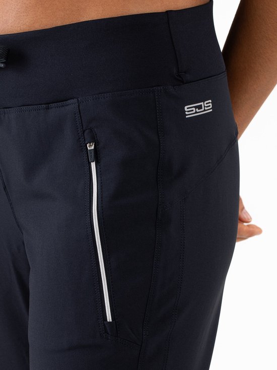 Close-up van een donkerblauwe trainingsbroek met ritszakken en logo.