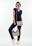 Model in donkerblauw shirt en spijkerbroek met een lichtroze handtas en een bijpassende crossbody tas.