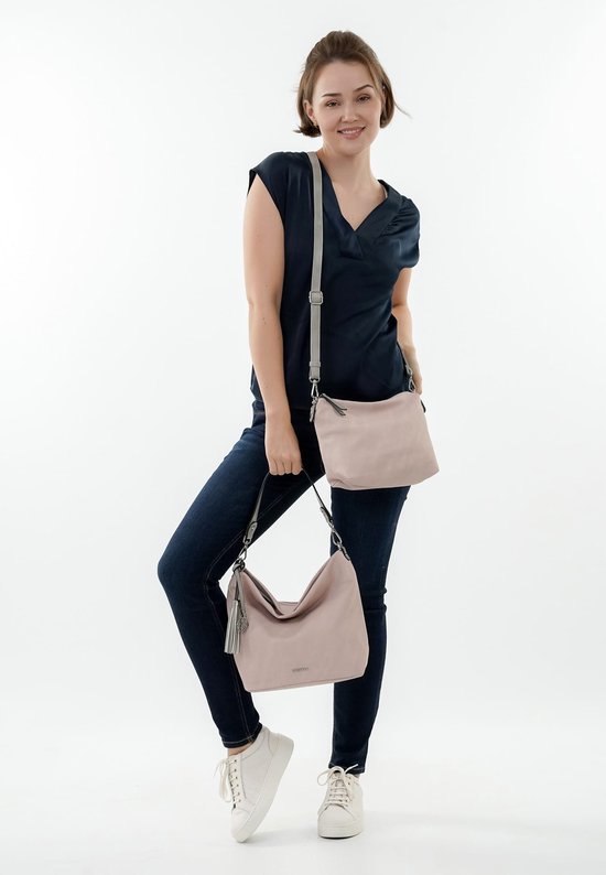 Model in donkerblauw shirt en spijkerbroek met een lichtroze handtas en een bijpassende crossbody tas.