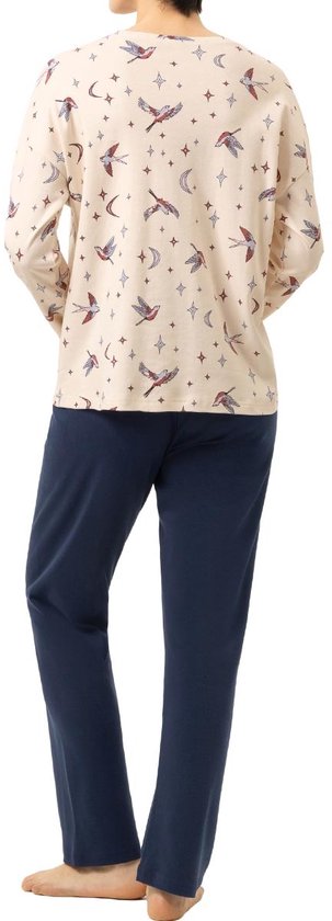 Model met lange mouwen pyjamaset in crème met vogels, sterren en manen print, met marineblauwe broek. Achteraanzicht.