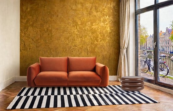 Gouden textuurverf op de muur met een oranje bank, gestreepte deken en een bruin bijzettafeltje.