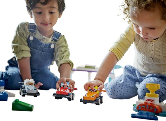 Deux enfants jouent avec des voitures LEGO Duplo rouges, oranges et grises.
