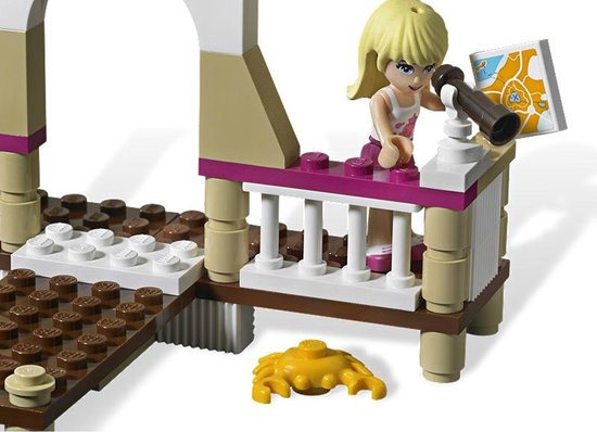 Blond meisje met telescoop en kaart op een terras met wit hek, paarse accenten en houten vloer.