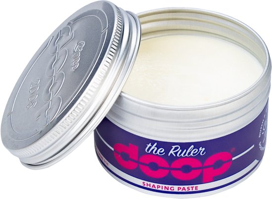 Open zilverkleurige pot met witte crème. Het blauwe label heeft roze letters: 'the Ruler doop SHAPING PASTE'.
