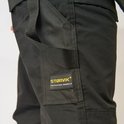Detailopname van het STØRVIK PROFESSIONAL WORKWEAR label op een zwarte broek.