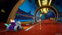 Een speelgoedauto met vlammen uit de uitlaat rijdt over een feloranje circuit in een futuristische blauwe tunnel.