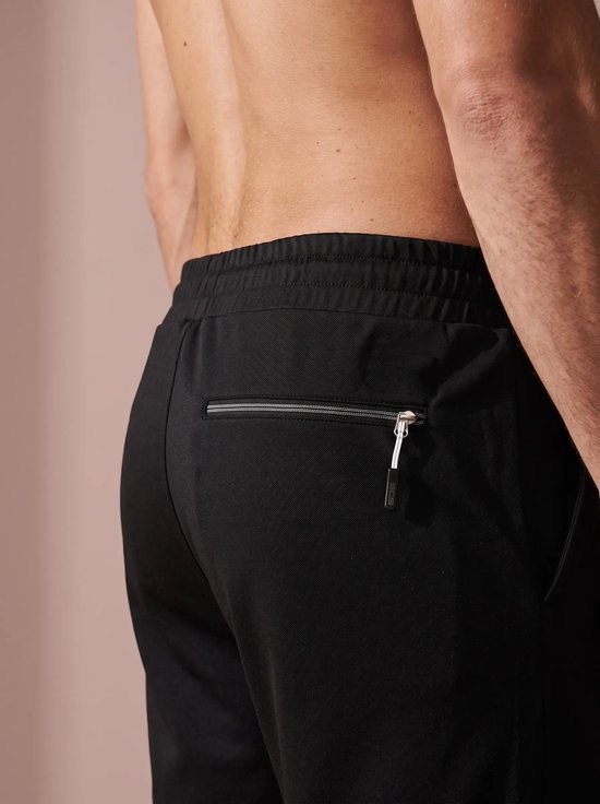 Achterkant van een zwarte sportshort met een horizontale ritszak op de bil.