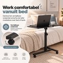 Zwarte verrijdbare laptoptafel bij een bed, met vier soepele wieltjes voor eenvoudige verplaatsing.