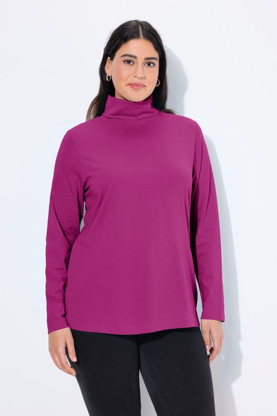 Model draagt een bessenkleurig shirt met lange mouwen en een colkraag, gecombineerd met een zwarte broek.